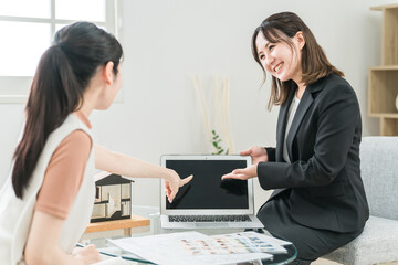 Fototapeta premium パソコンを使って商談・説明・提案するハウスメーカー・不動産屋のビジネスウーマンと女性客 