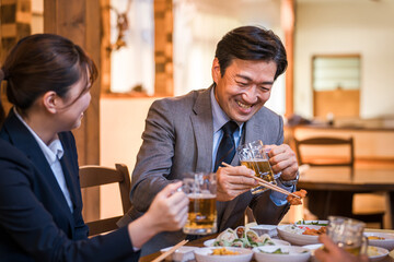 居酒屋で楽しい忘年会・新年会・飲み会・宴会をする仕事仲間・同僚・上司部下の男女
