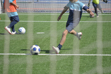 Obraz premium pallone da calcio sul campo da gioco tra le gambe di giocani calciatori