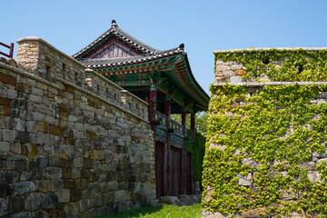 Summer view of ivy with green leaf on the stone rampart with entrance door and pavilion at Military Headquarters of Jeolla-do Province near Gangjin-gun, South Korea
