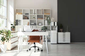 Interior of office with workplace, shelf unit and water cooler
