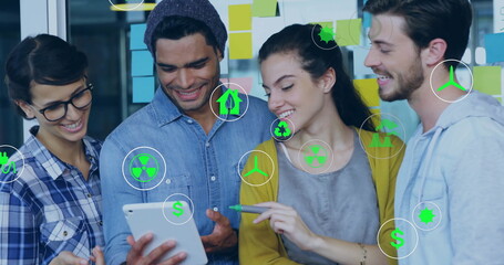 Image of ecology icons over diverse colleagues using tablet in office
