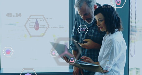 Image of ecology icons over diverse colleagues using laptop in office