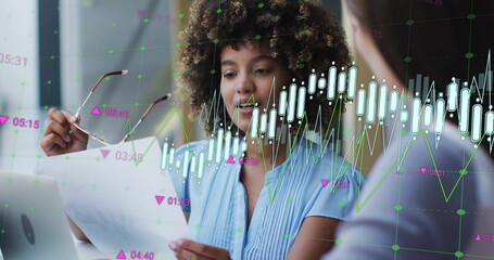 Image of graph processing data over biracial casual businesswoman talking to colleague at office