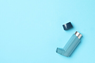 Asthma inhaler on light blue background, top view. Space for text