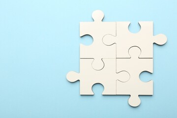 White puzzle pieces on light blue background, top view. Space for text