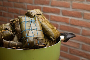 Hallacas ready to serve in a pot. Bricks background with copy space. Traditional Christmas food in Venezuela