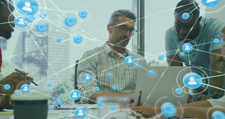 Image of network of connections with icons over diverse colleagues using laptop in office