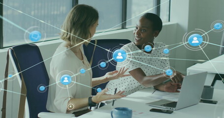 Image of network of connections with icons over diverse female colleagues using laptop in office