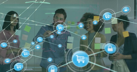 Image of network of connections with icons over diverse colleagues discussing work in office