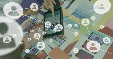 Image of network of connections with icons over diverse colleagues discussing project