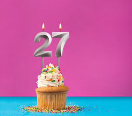 Lit birthday candle with the number 27 - Celebration card on violet and blue background