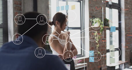Image of network of connections with icons over diverse colleagues at meeting in office