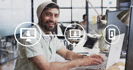 Image of network of connections with icons over diverse colleagues working in office