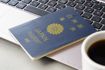 日本のパスポート（一般旅券5年用紺色）とパソコンで、長期休暇の前に、海外旅行を計画しているイメージ
