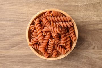 Raw fusilli pasta in bowl on wooden background, Table top view