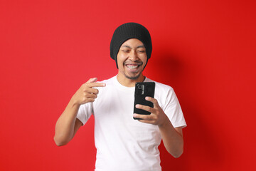 Happy Indonesian man receives a good news notification on his phone about special offers, discounts, and great deals during an Indonesian Independence Day promo event. Isolated on a white background.