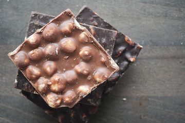 A stack of delicious gourmet chocolate bars topped with nuts on a wooden surface