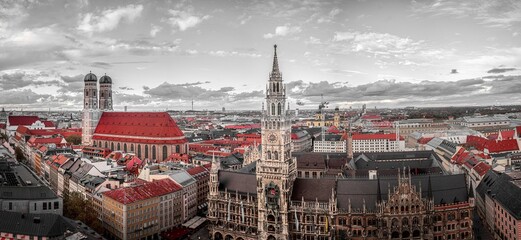 Naklejka premium A view of the city of Munchen, Germany, from above with the spires and towers of the city's churches and buildings standing tall against a cloudy sky.