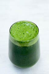 A close-up shot of a vibrant green smoothie or juice in a clear glass