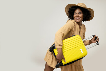 Young African American woman in a hat with a suitcase