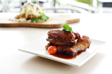 A close-up photo of a plate overflowing with Korean fried chicken wings. The wings are glazed in a glossy red sauce and sprinkled with white sesame seeds.