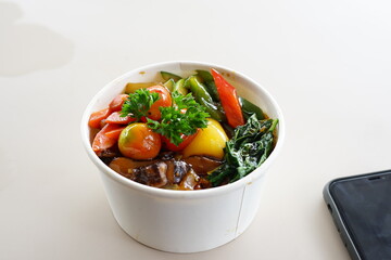 A bowl of food with a variety of vegetables and meat