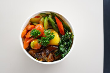 A bowl of food with a variety of vegetables and meat