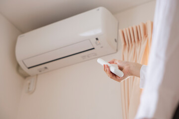 A woman turning on the air conditioner. Person turning off the air conditioner.  エアコンのスイッチをつける女性。エアコンのスイッチを消す人。