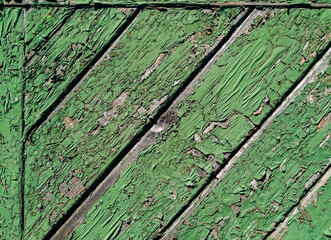 Old green cracked paint on top of a wooden door. Texture and grunge background, diagonal orientation.