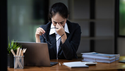 Fototapeta premium Tired asian businesswoman with headache at office, feeling sick at work, copy space