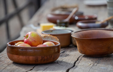 Ripe apples in a ceramic bowl close-up, pottery on a wooden table, medieval lifestyle, still life