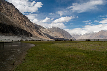 the river with blue sky and sandstone mountains in nubra valley, leh ladakh, india