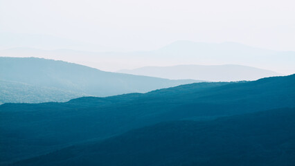 Fototapeta premium Mountain range with visible silhouettes through morning colorful fog. Calm evening landscape in the mountains at sunset. Photo wallpapers. Natural background. Panorama. Crimea, Ukraine