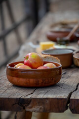 Ripe apples in a ceramic bowl close-up, pottery on a wooden table, medieval lifestyle, still life