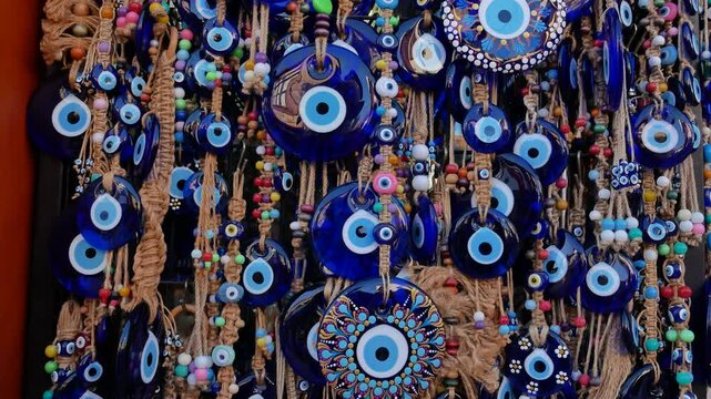 Many amulets of the Turkish eye hang on a stand in a souvenir shop. Panorama.