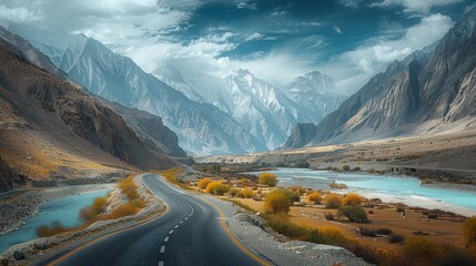 Scenic highway winding through snow-capped mountains alongside a river under a cloudy sky
