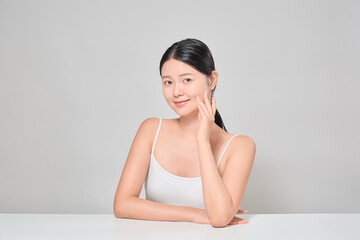 A female model touching her clear and clean skin with her fingers.