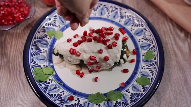 Mexican traditional food Chiles en Nogada for independence day, Poblano chili stuffed with beef and pork, with pomegranate fruit, nogada, vegetables.   