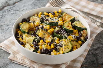 Roasted Zucchini salad with black beans, corn, garlic and cheese close-up in a bowl on the table. Horizontal