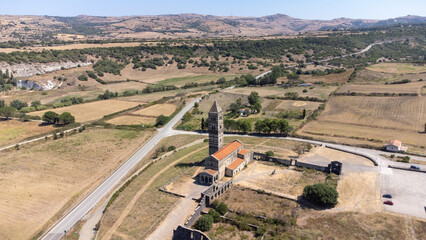 High angle view of the Basilica di Saccargia a romanesque church in the province of Sassari in Sardinia, Italy, surrounded by countryside landscape and mountains. Cultural religious tourism