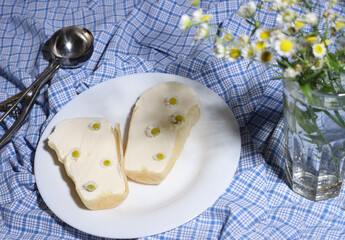 ice cream decorated with chamomile flowers lies on a white plate and on a blue blanket