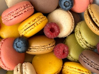 Macarons in different colors and tastes and raspberries and blueberries 
