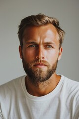 Obraz premium Close-up portrait of a handsome young man with a beard wearing a white shirt