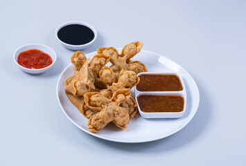 Batagor,(Fried Tofu Meatballs), served on a serving plate with peanut sauce, sambal, and chili sauce. This is authentic street food from Bandung Indonesia. Perfect for recipes, articles or any cooking