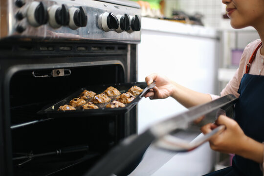 Cheerful Young Woman Baking Cookies Into oven