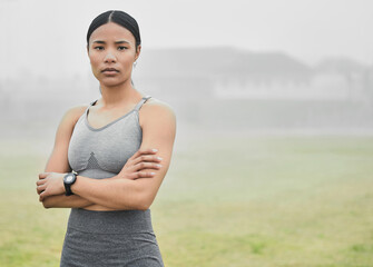 Black woman, portrait and confidence outdoor for fitness, wellness and health goals achievement in morning. Athlete, face and crossed arms on field for workout, training and exercise with headphones