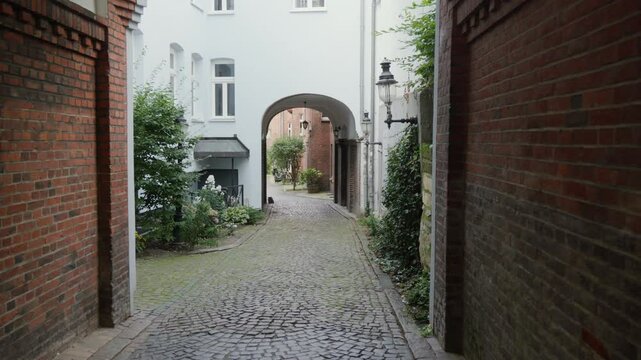 Charming cobblestone alley with brick arches in historic Flensburg. Perfect for travel films and heritage documentaries.