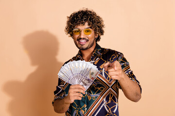 Obraz premium Photo portrait of attractive young man hold money fan point you dressed stylish print clothes isolated on beige color background