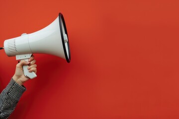 Hand holding a megaphone against a red background